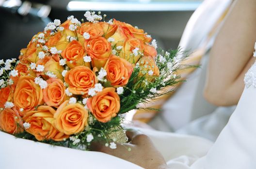 Close-up of a vibrant bridal bouquet with orange roses and baby's breath.
