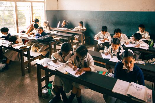 Elementary school children studying in a classroom, focusing intently on their work.