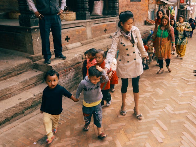 Kids Walking On The Side Of The Street Along With Their Guardians