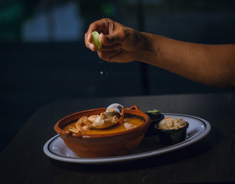 Hand Squeezing Lime Into Soup