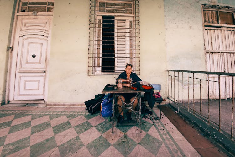 A Woman Sewing Fabrics Looking At The Camera