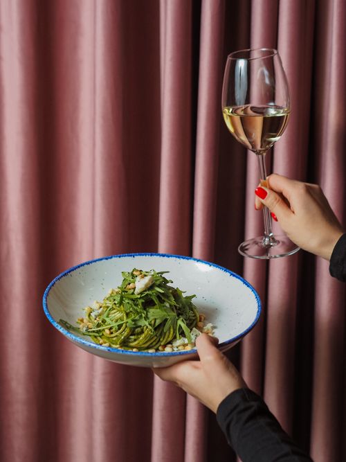 Free Close-up of pasta plate and wine glass held against elegant curtains. Stock Photo