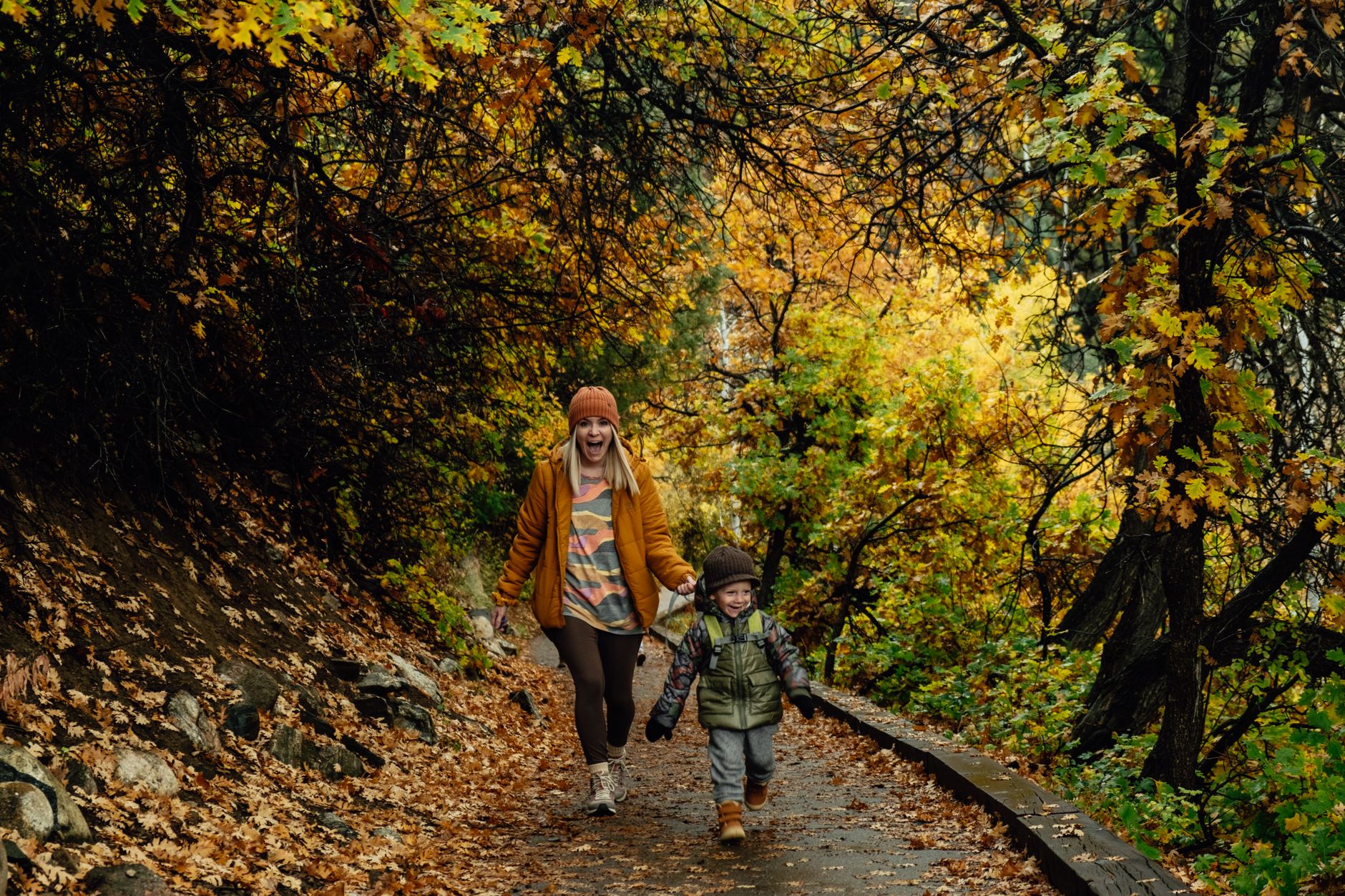 A mother and child enjoying a walk amidst vibrant autumn foliage.