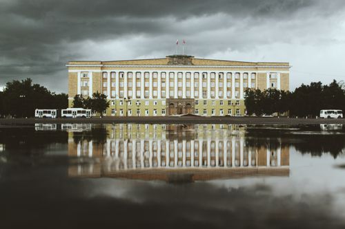 Free A historic building reflected in water under dramatic clouds in Veliky Novgorod, Russia. Stock Photo