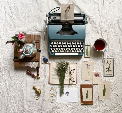 Free Aesthetic flat lay featuring vintage typewriter, flowers, and tea on a textured background. Stock Photo