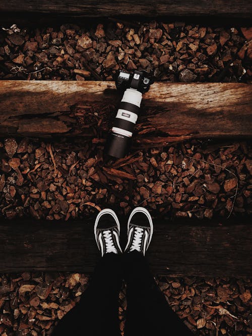 Person Wears Black-and-white Vans Low-top Sneakers Stands In Front of Black Dslr Camera