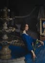 Woman in Blue Dress Holding Lily Sitting on Water Fountain