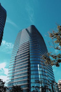 一座时尚的现代摩天大楼，其反光玻璃映衬着清澈的蓝天，展现了城市建筑的魅力