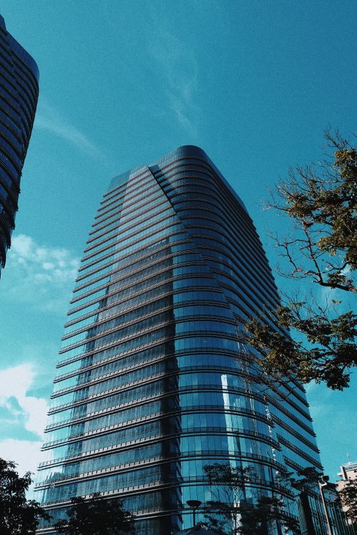 Free A sleek modern skyscraper with reflective glass against a clear blue sky, showcasing urban architecture. Stock Photo
