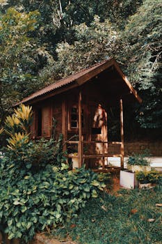 Brown Wooden House Near Plants and Trees with the Quote "To me, it doesn't matter how good you are. Sport is all about playing and competing. Whatever you do in cricket and in sport, enjoy it, be positive and try to win." written on it and have average color value #404030