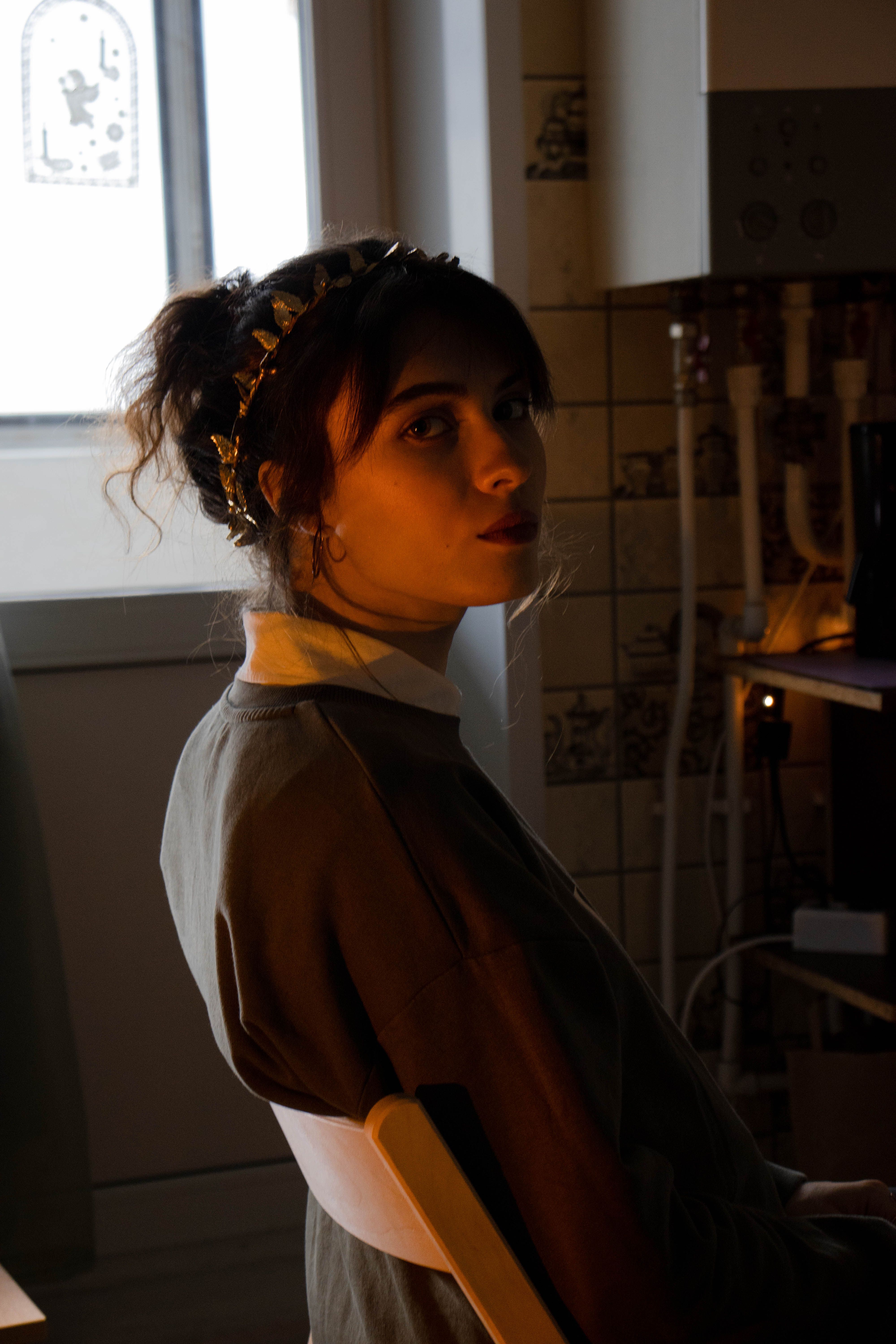 Portrait of a woman sitting indoors with soft warm lighting and a headband.
