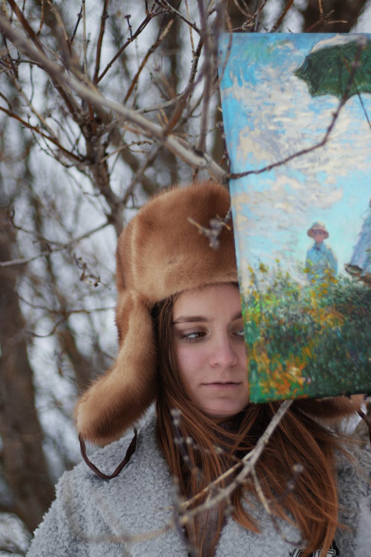 Girl In Outerwear With Painting Near Winter Tree