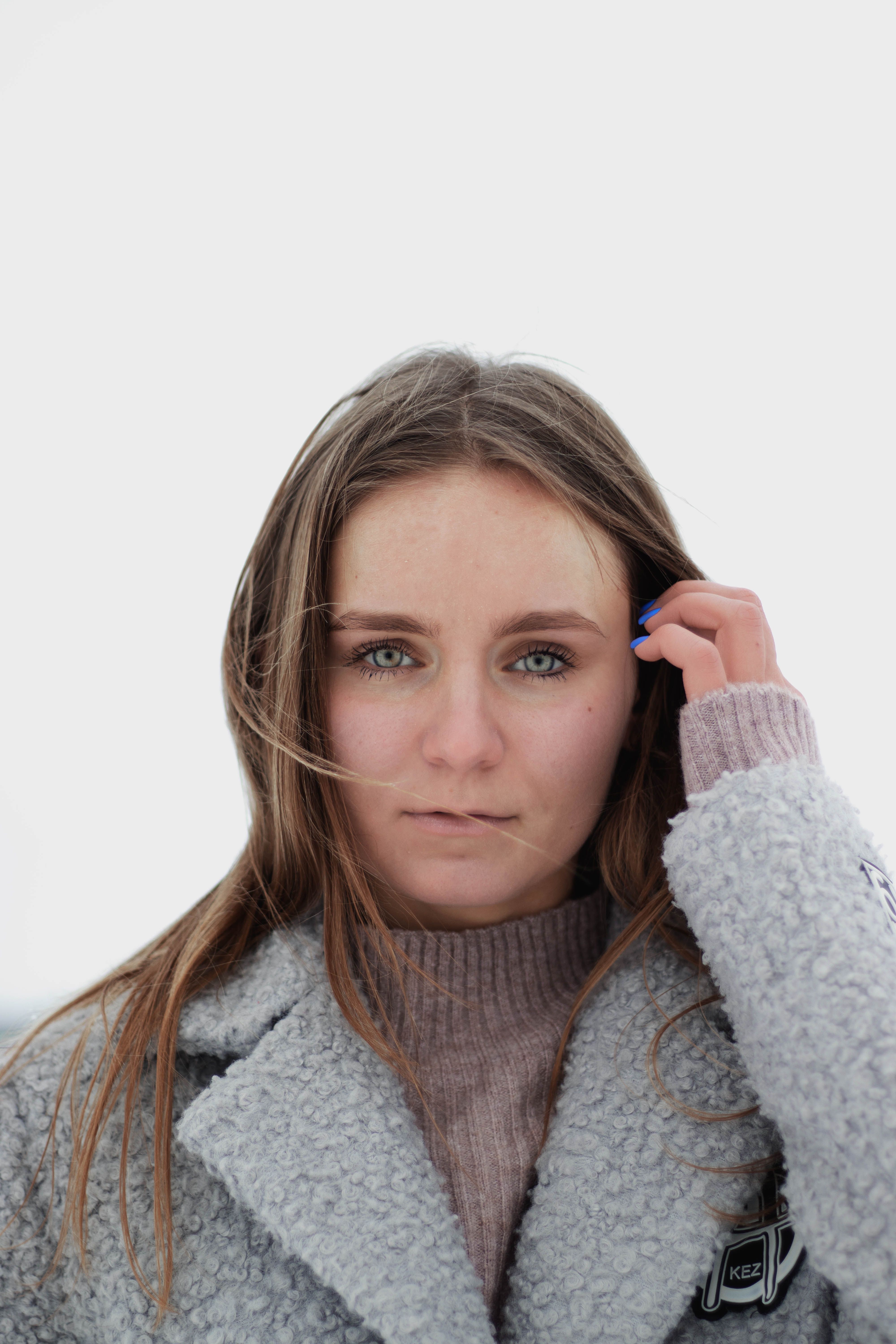 Close-up of a young woman in winter clothing, with a neutral background.