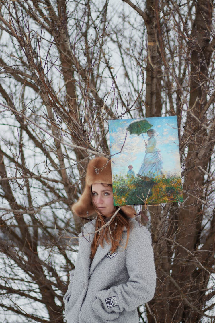 Woman With Painting Wearing Warm Clothing On Winter Landscape