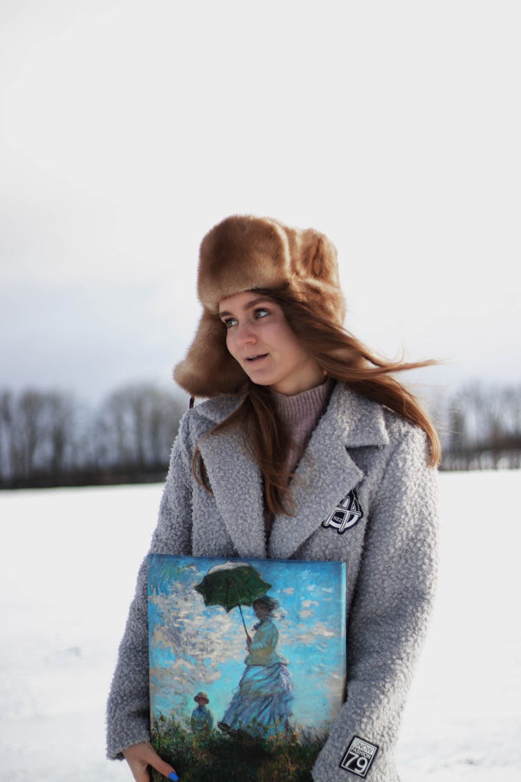 Woman With Painting Wearing Warm Clothing On Winter Landscape