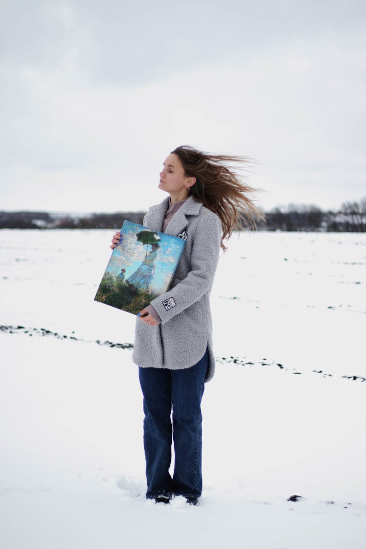 Woman With Painting Wearing Warm Clothing On Winter Landscape