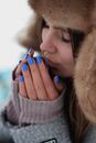 Woman Wearing Fur Hat Heating Hands at Mouth