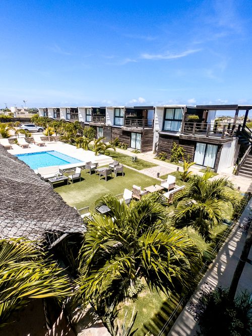 Free Aerial view of a luxury hotel with a pool surrounded by greenery, perfect for summer vacations. Stock Photo