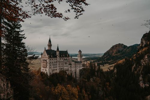 Free Bavaria's Neuschwanstein Castle surrounded by autumn trees, showcasing Germany's picturesque architecture. Stock Photo