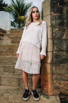 Chic woman poses in modern outfit on rustic stone steps, embodying outdoor fashion elegance.