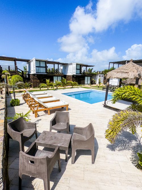 Free A serene outdoor resort setting featuring a modern swimming pool, loungers, and tropical plants under a clear blue sky. Stock Photo