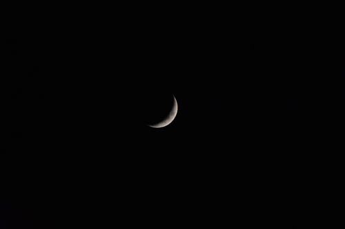 Free A serene crescent moon set against a vast, dark night sky, symbolizing tranquility and mystery. Stock Photo