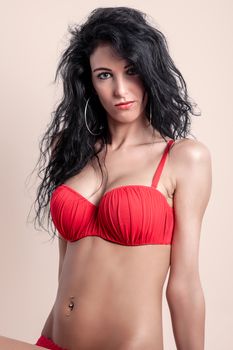 Striking studio portrait of a confident woman wearing red lingerie, showcasing beauty and fashion.