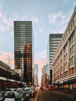 Vancouver city street view showcasing skyscrapers and bustling urban traffic at sunset.