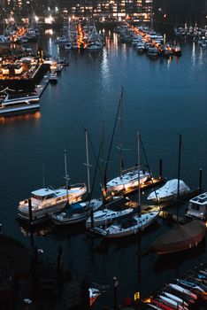 A serene evening at Vancouver marina with boats and city lights reflecting on the water.