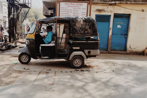 Free Auto rickshaw with driver on a sunny street in Udaipur, capturing local urban life. Stock Photo