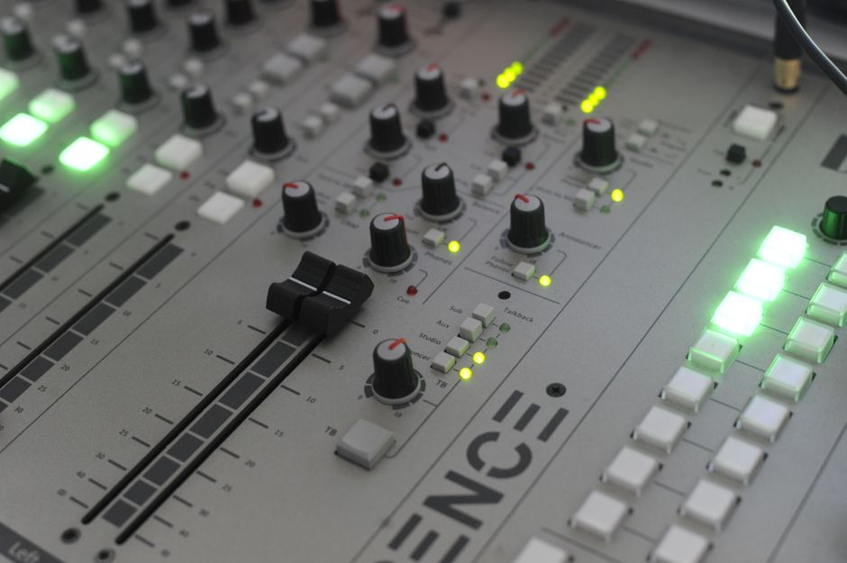 Detailed close-up of a modern audio mixing console with illuminated controls and sliders.