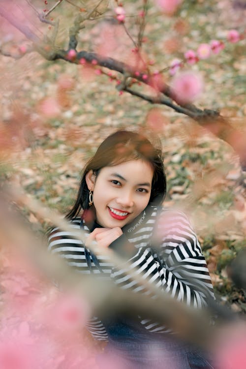 Young Woman Between Branches of Cherry Blossom 