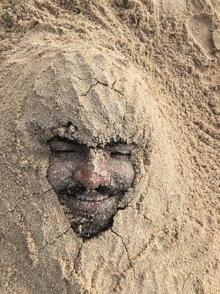 Portrait Of Man Buried In Sand On Beach