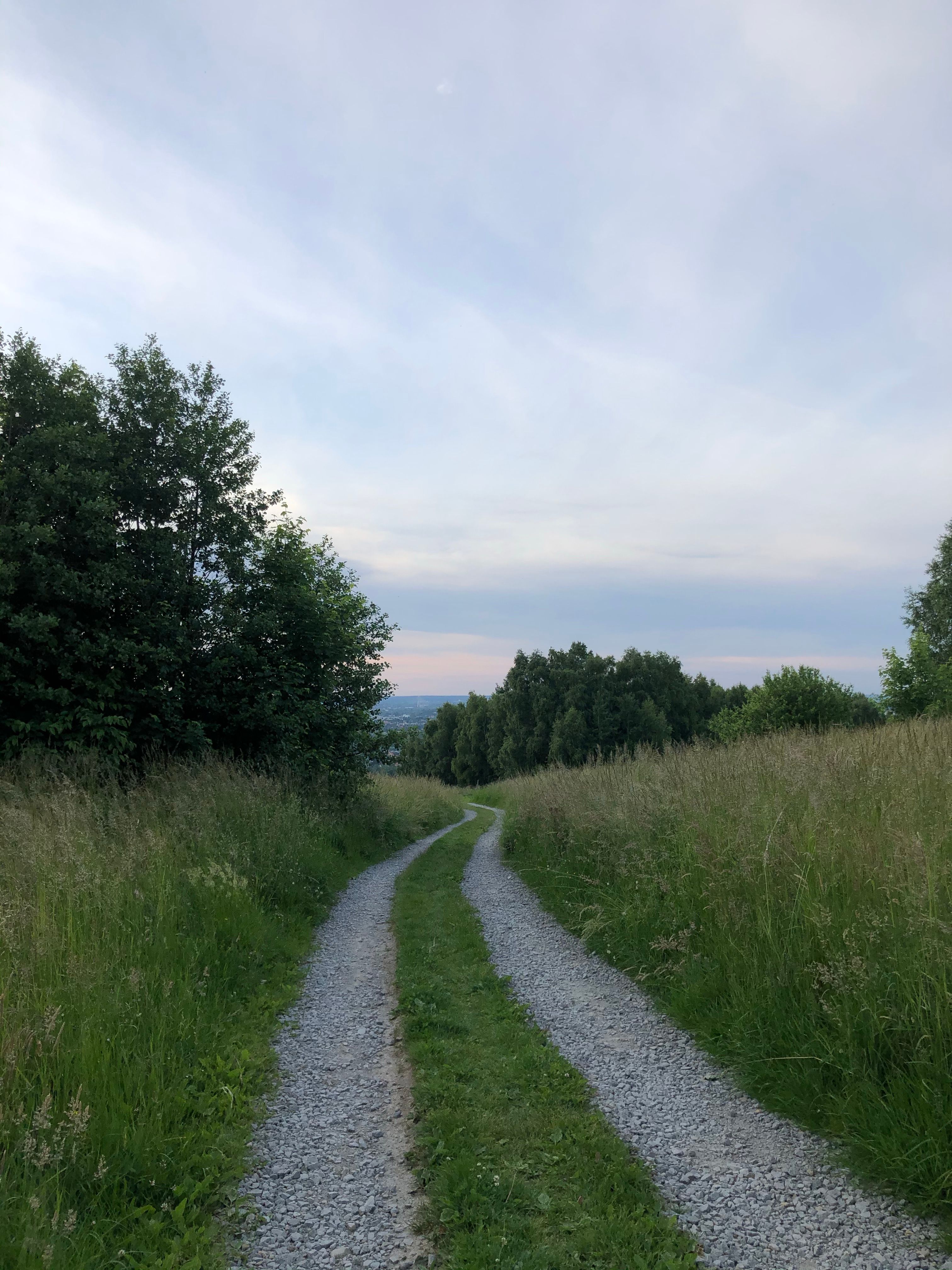 Gravel road through countryside at dusk — photo by Łukasz on Pexels