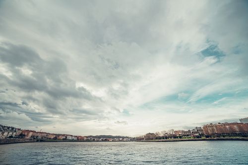 Free Dramatic clouds over the Oleiros waterfront in Galicia, Spain, showcasing urban architecture and tranquil waters. Stock Photo