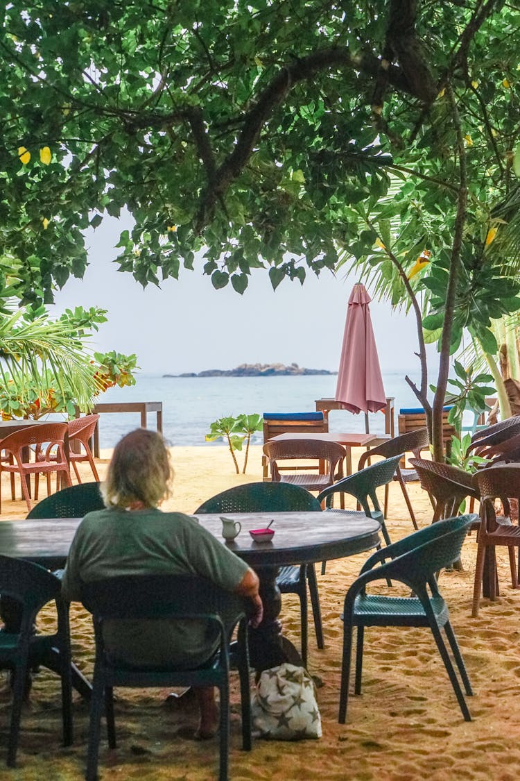 Back View Of A Man Sitting On A Beach 