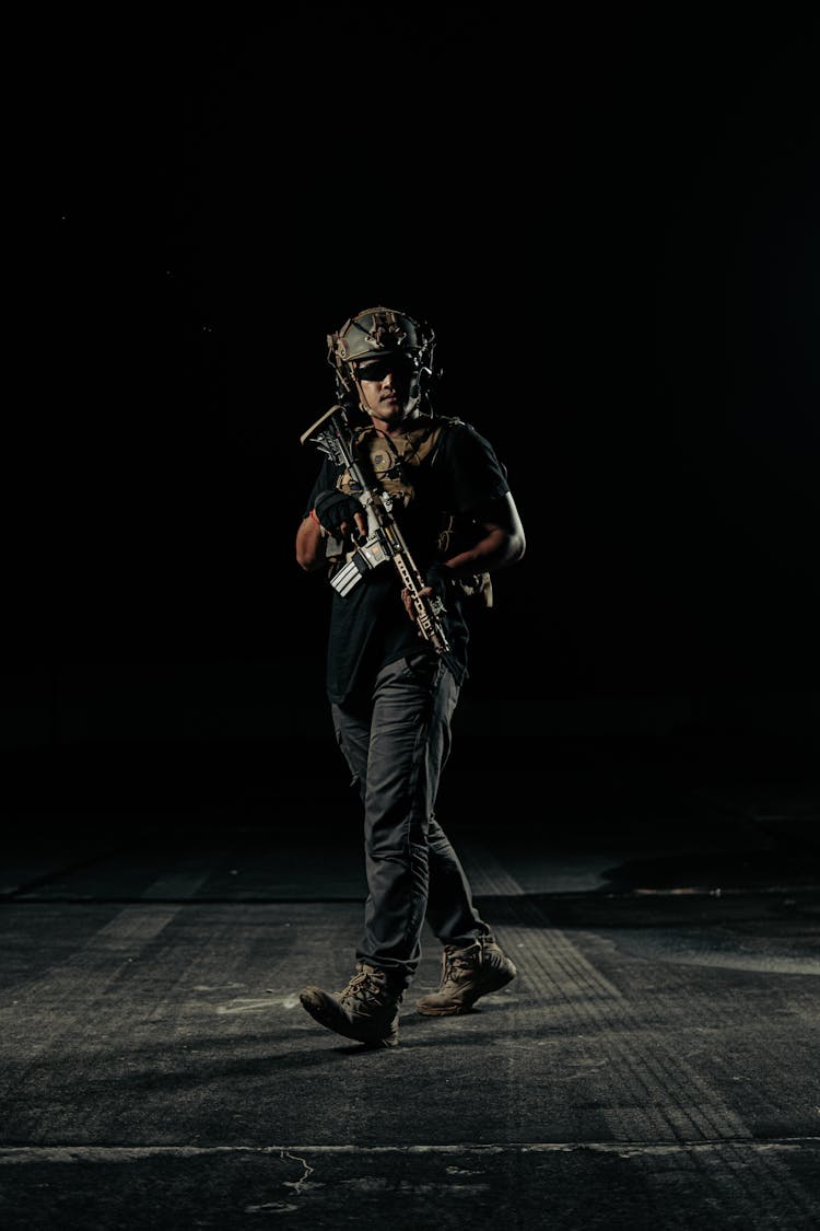 Black Image Of A Man Wearing A Helmet Walking With A Machine Gun