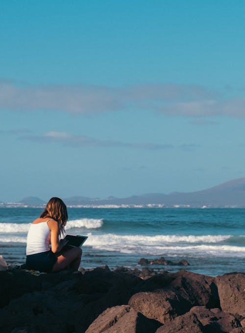 Woman Sitting on Rock by the Sea