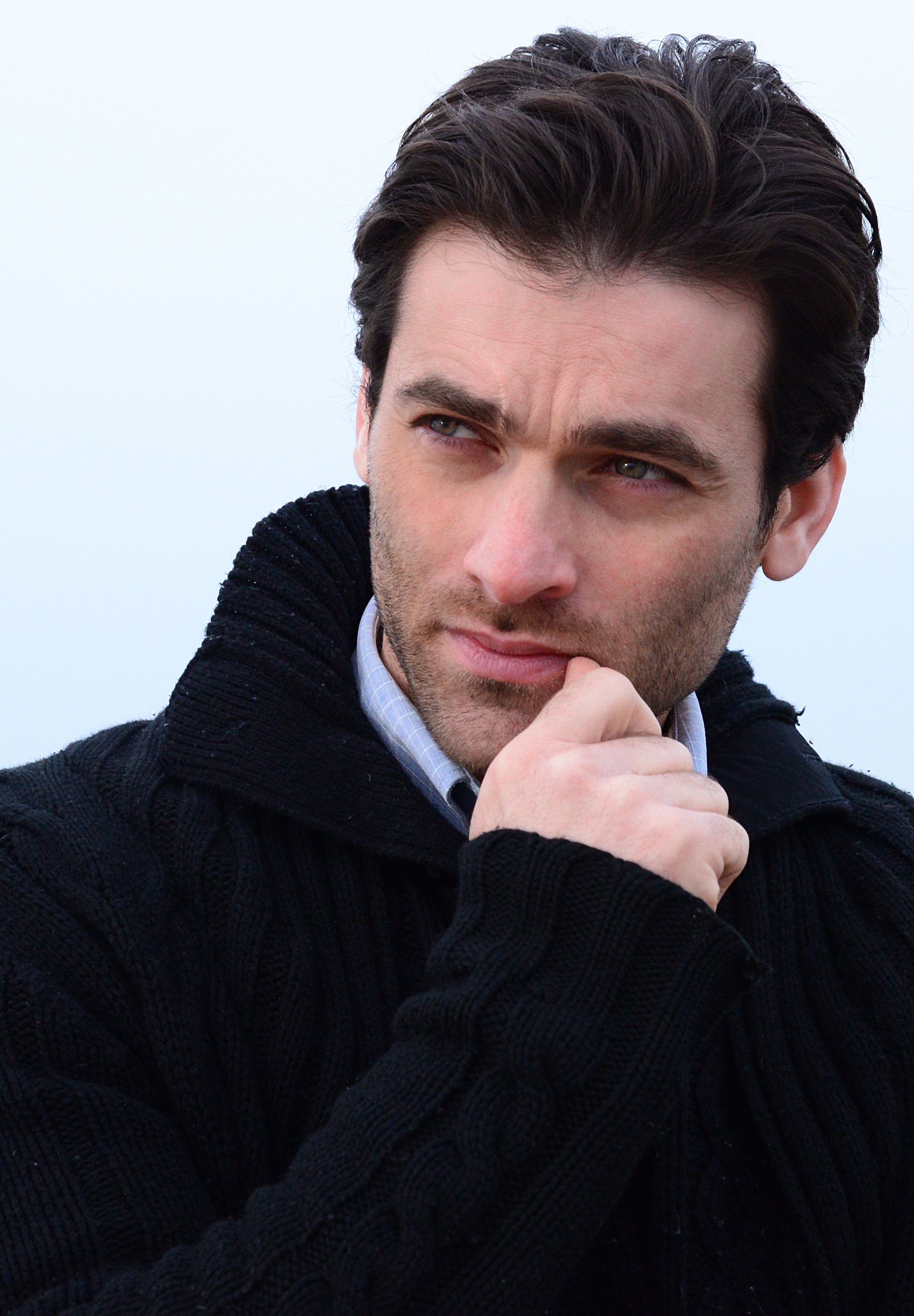 A thoughtful man in a warm sweater posing outdoors, showcasing a classic, contemplative expression.