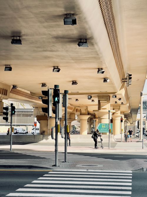 Free Pedestrian lane and traffic lights under a bridge in Dubai's cityscape. Stock Photo