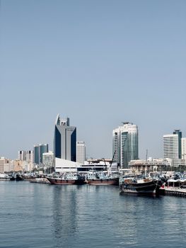 Scenic view of Dubai Marina with traditional boats and skyscrapers under a clear sky.