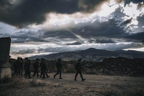 Soldiers Walking on a Brown Field