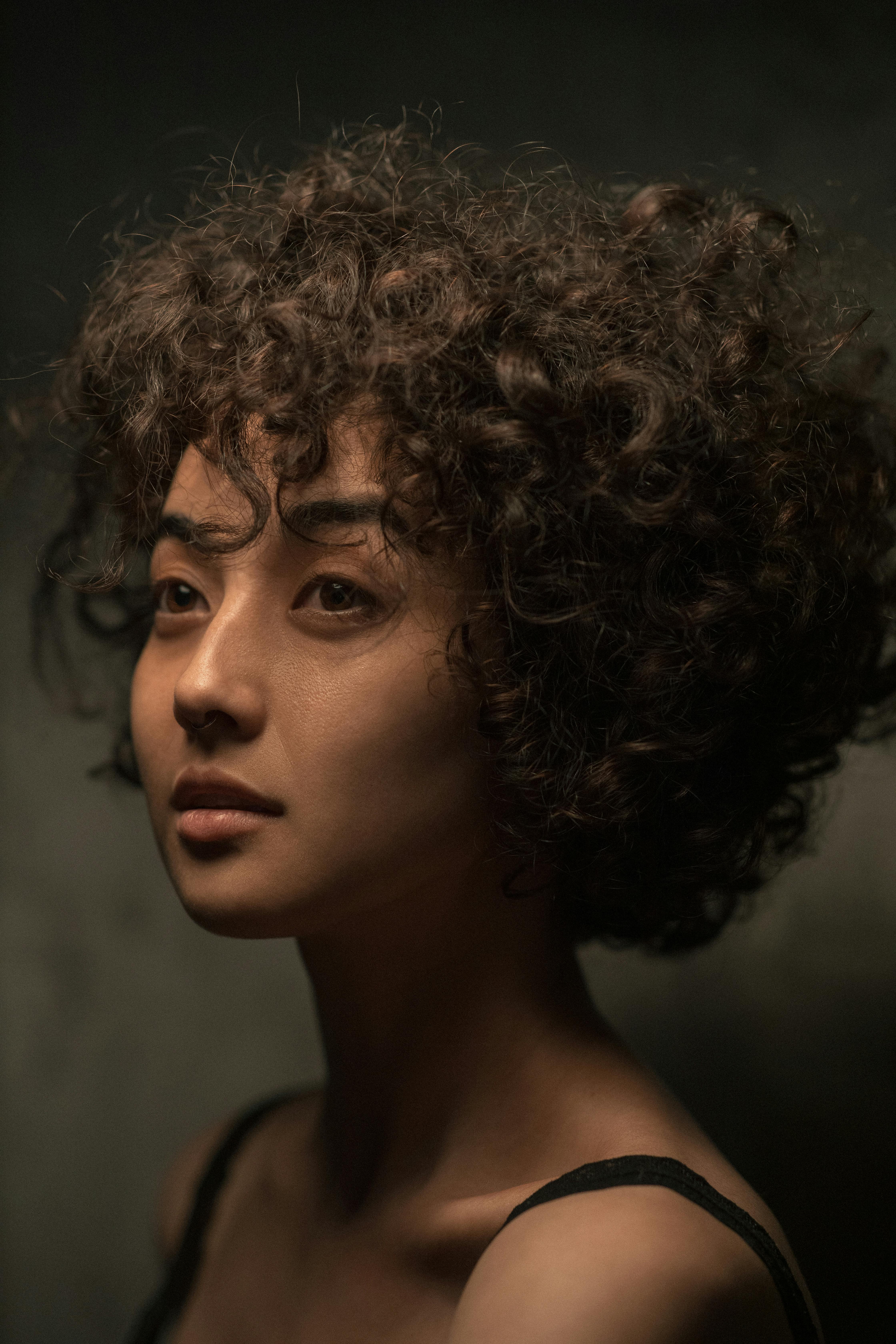 closeup portrait of young adult woman with dark tanned skin and curly hair  attractive face mouth slightly open teeth sunbeams in background from  behind pretty face Generative AI  Backgrounds  Textures 