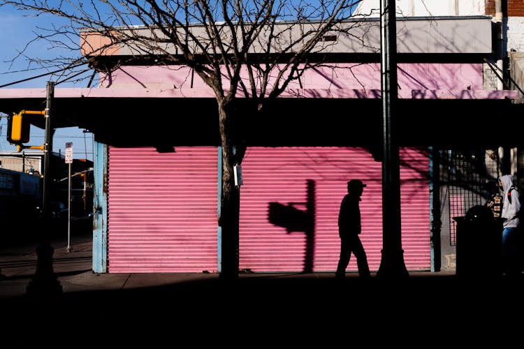 Silhouette Of A Man Walking On The Street Near Closed Business Establishment