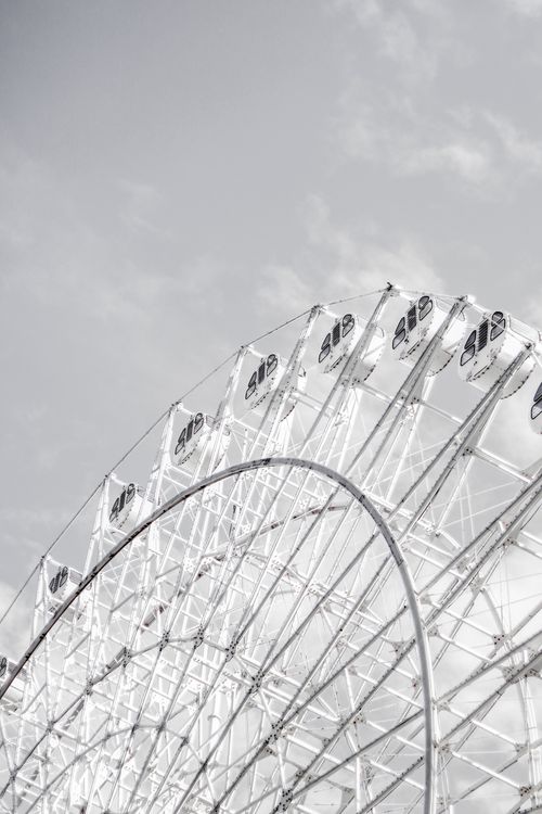 Free A striking monochrome photograph capturing a ferris wheel's structure against a cloudy sky. Stock Photo