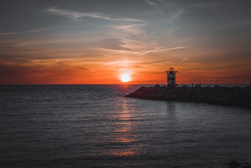 Free A dramatic sunset over the sea with a lighthouse in The Hague, Netherlands. Stock Photo