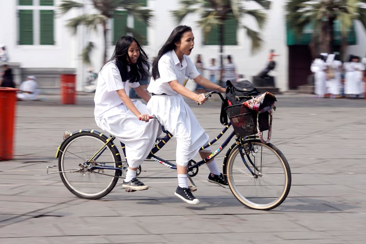 Girls Riding On A Tandem Bicycle 