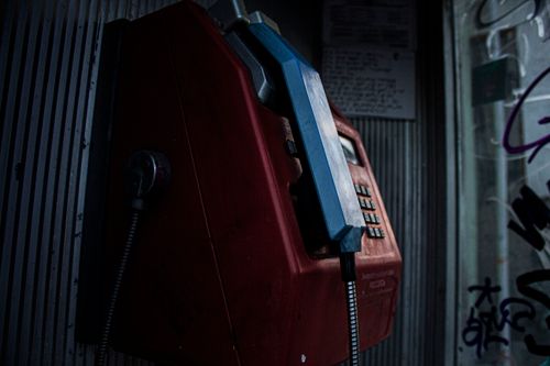 Free A close-up view of a vintage red payphone, highlighting its classic design in a urban setting. Stock Photo