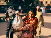 Woman Wearing a Red Shawl Carrying a Sack