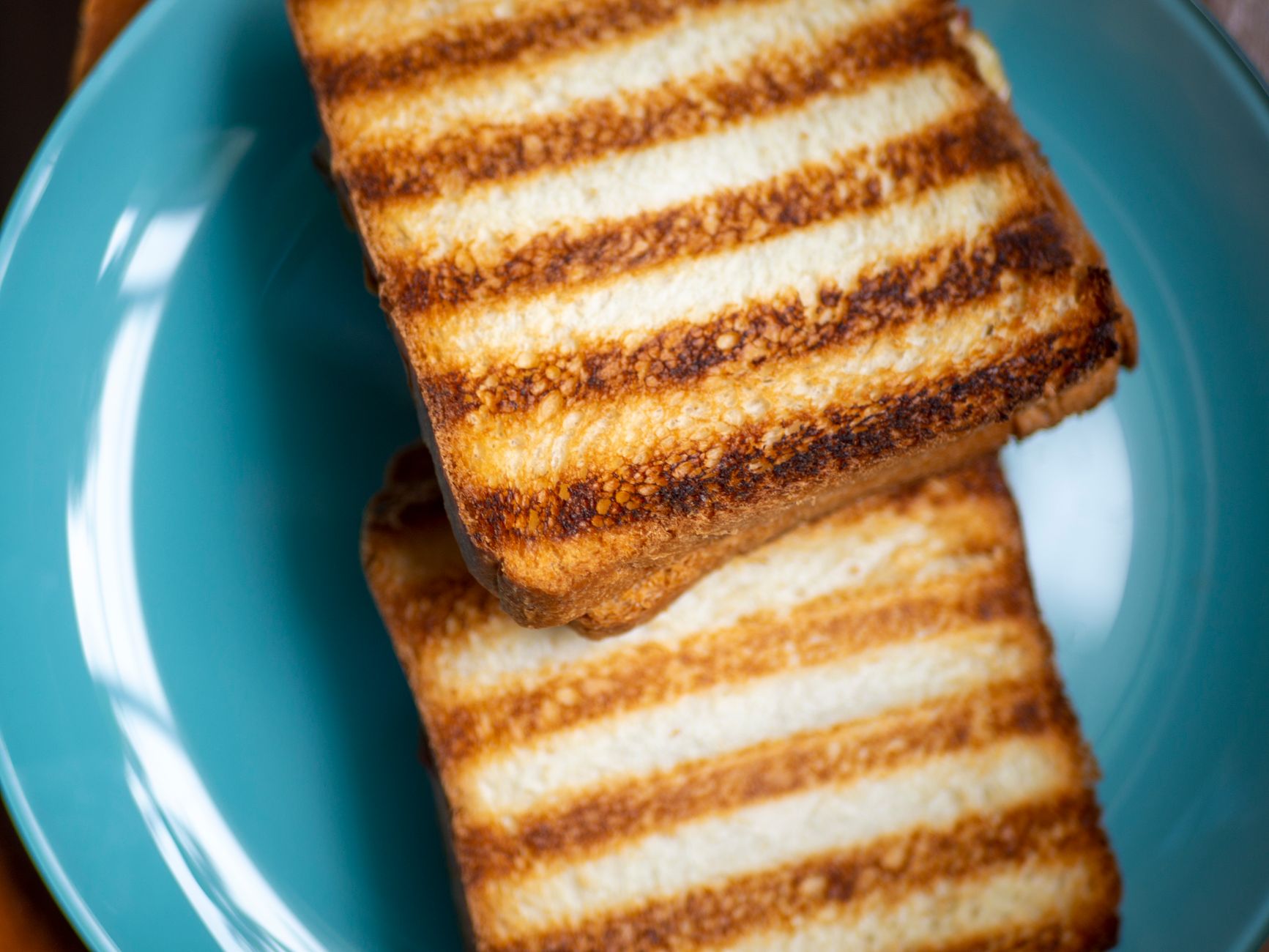 Close-up of perfectly toasted bread slices on a vibrant blue plate.